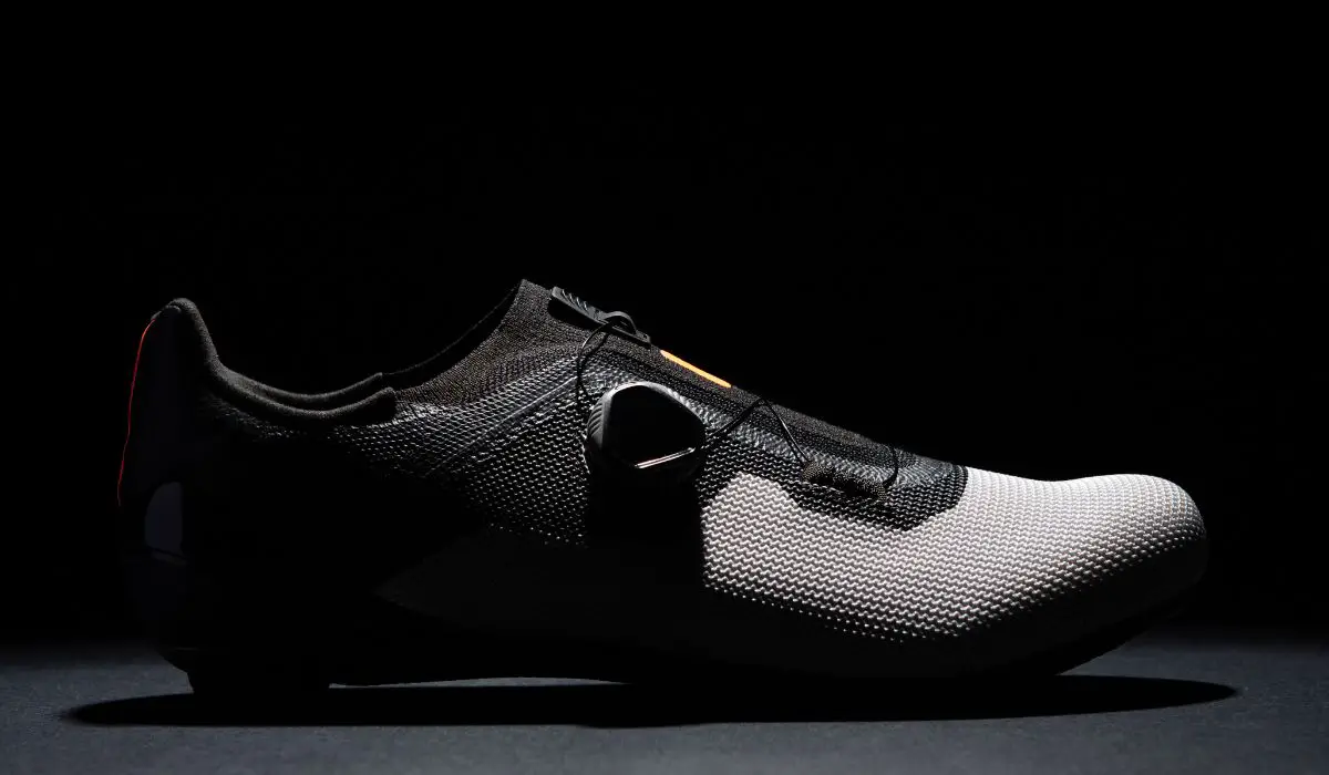 A black and grey cycling shoe in a dark shadowed space, looking sleek and futuristic.