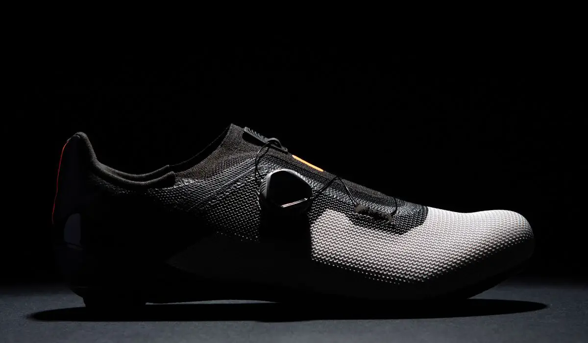 A black and grey cycling shoe in a dark shadowed space, looking sleek and futuristic. 