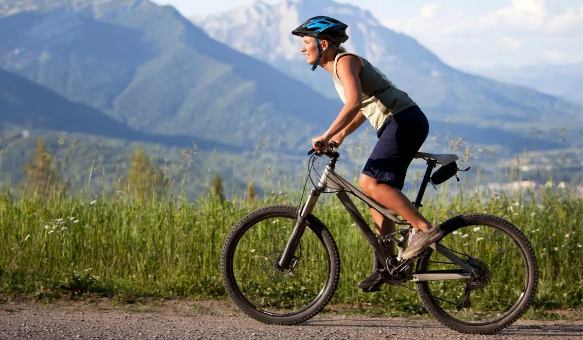 A woman riding a mountain bike on a gravel mountain path.