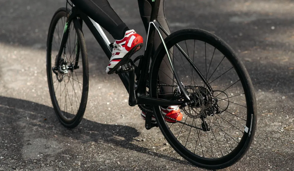 A person pedaling a bike, photo at tire level.