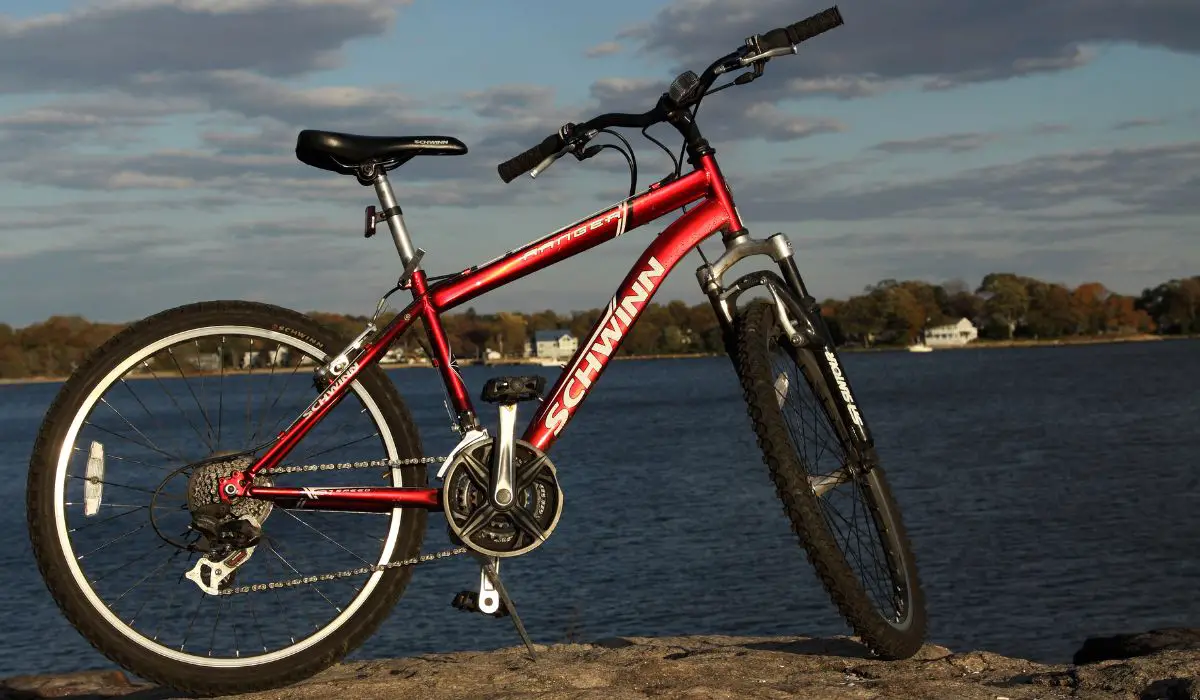 A red schwinn mountain bike next to the ocean on a path. 