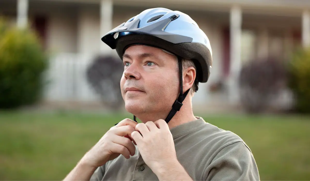 A man putting on a bicycle helmet.