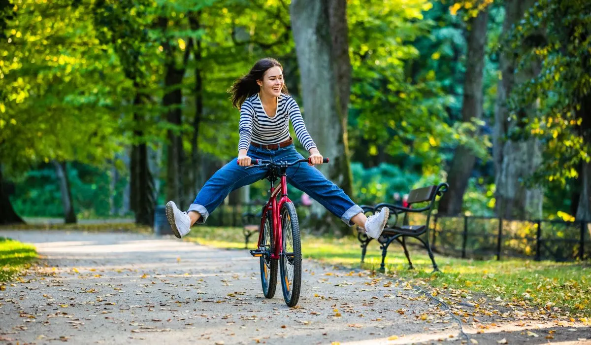 A girl on a casual bike ride with her legs out and off the pedals having fun.