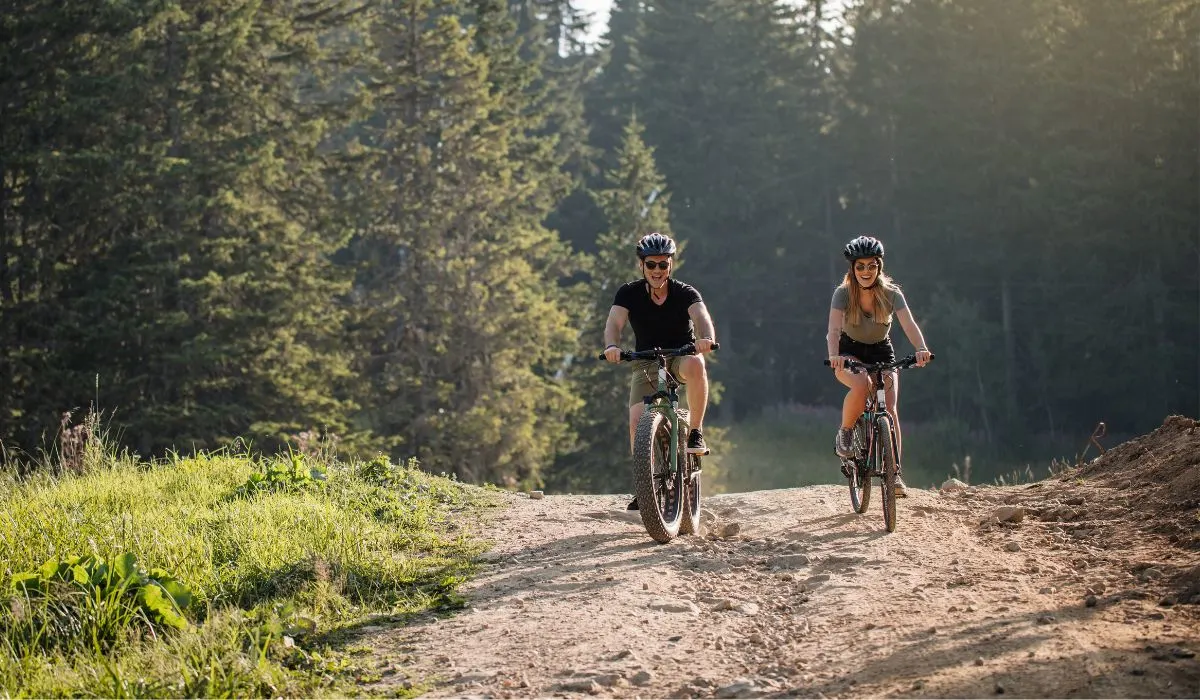 2 people riding mountain bikes on a dirt path. 